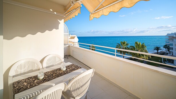 A balcony with a table and chairs, overlooking a clear blue sea and a coastal landscape. - Apartment Costa Bella close to the Beach with Shared Pool & Wi-Fi (Altea)