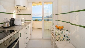 A compact kitchen with a view of the ocean, a balcony with a table and chairs, and a small seating area. - Apartment Costa Bella close to the Beach with Shared Pool & Wi-Fi (Altea)
