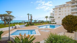 A swimming pool with a view of the sea, surrounded by greenery and a building with balconies. - Apartment Costa Bella close to the Beach with Shared Pool & Wi-Fi (Altea)