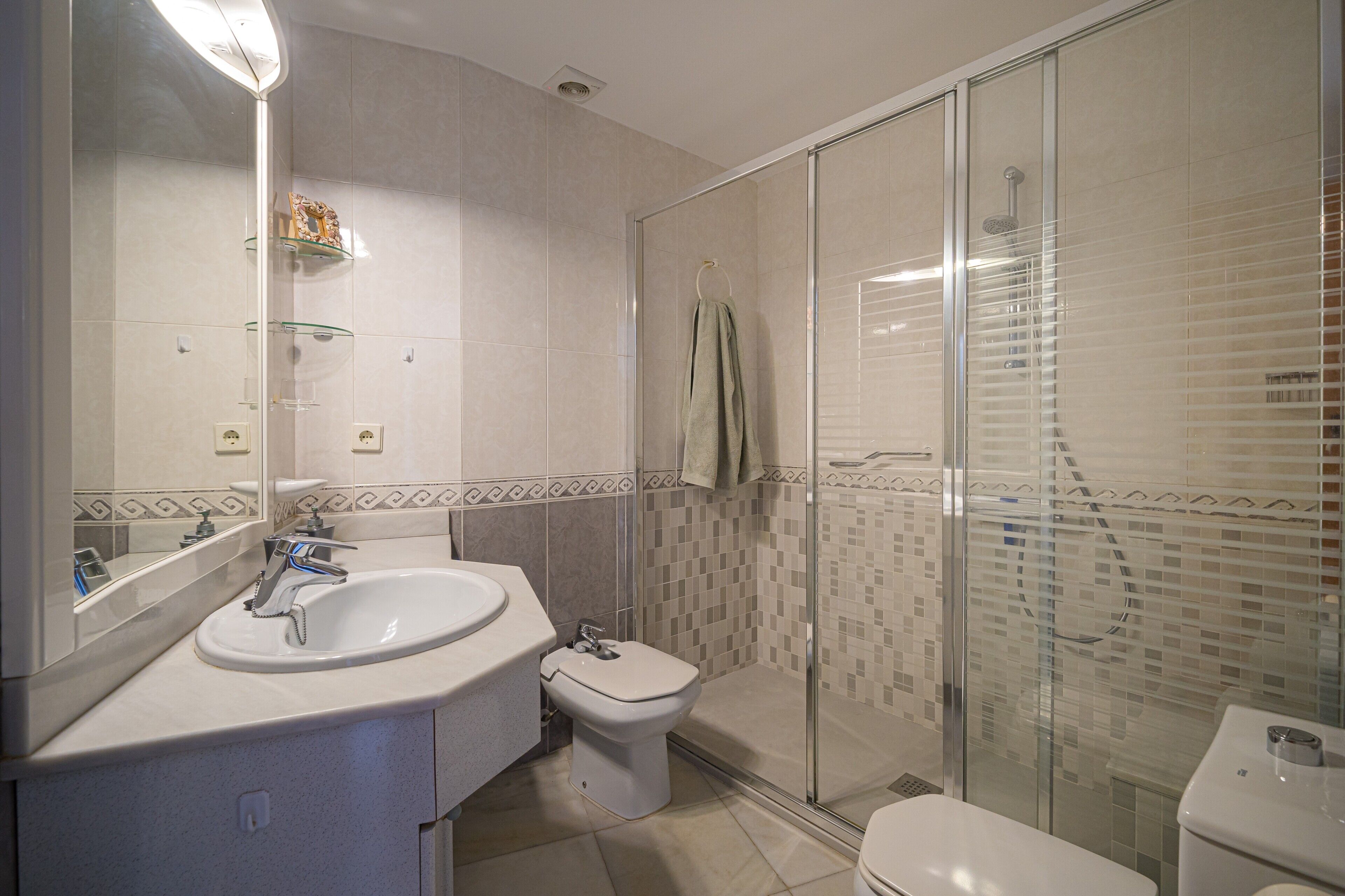 Une salle de bain moderne avec une douche à parois de verre, un lavabo blanc et des toilettes.