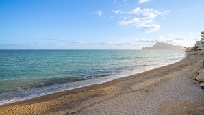 A beach with a rocky shoreline, calm sea, and a distant mountain. - Apartment Costa Bella close to the Beach with Shared Pool & Wi-Fi (Altea)