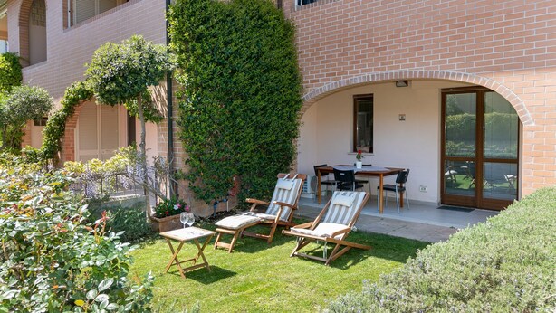 A patio with outdoor furniture, a brick building, and a large tree. - Studio Residence Valle Fiorita with Shared Pool & Wi-Fi in Riotorto (Piombino)