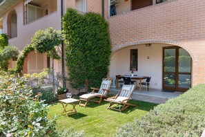 A patio with outdoor furniture, a brick building, and a large tree. - Studio Residence Valle Fiorita with Shared Pool & Wi-Fi in Riotorto (Piombino)