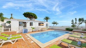 A pool area with lounge chairs, a swimming pool, and a white building with a balcony. - Villa Brigida with Sea View, Heated Pool & Wi-Fi (São Rafael)