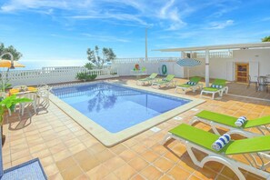 A swimming pool with lounge chairs, a table, and a view of the sea. - Villa Brigida with Sea View, Heated Pool & Wi-Fi (São Rafael)