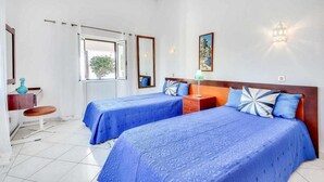 A bedroom with two beds, a desk, a chair, a window with curtains, and a wall-mounted light fixture. - Villa Brigida with Sea View, Heated Pool & Wi-Fi (São Rafael)