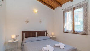 A bedroom with a bed, two bedside tables, a nightstand, a wooden ceiling, a window with curtains, and wall-mounted lights. - "Elegante appartamento centro" with 2 Terraces & Wi-Fi (san teodoro)