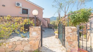 A stone pathway leading to a pink building with a lamp post and a gate. - "Elegante appartamento centro" with 2 Terraces & Wi-Fi (san teodoro)