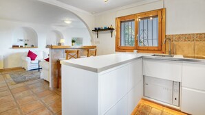 Une cuisine moderne avec des meubles blancs, un lave-vaisselle encastré et un cadre de fenêtre en bois.