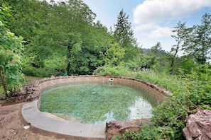 A circular pool with clear water, surrounded by a stone edge and lush greenery. - Holiday Home 'Chalet Nel Bosco' with Sea View, Shared Pool and Wi-Fi (Casarza Ligure)
