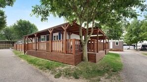 Un bâtiment en bois de style « RV » (véhicule récréatif), doté d’un porche et entouré d’arbres et de chemins de gravier.