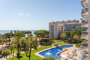 A hotel with a pool, palm trees, and a view of the sea.