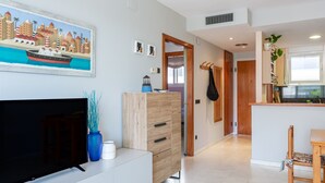 Uma sala de estar moderna com televisão de tela plana, armário de madeira e obras de arte na parede.