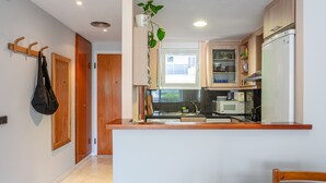 Cozinha moderna com armários de madeira, micro-ondas embutido e uma planta pendente.
