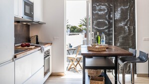 Una cocina moderna con armarios blancos, encimera de madera y comedor con mesa y sillas de madera.