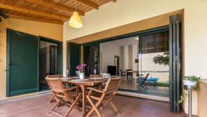 Un patio con una mesa redonda y sillas, un colgante de luz y un ventanal corredero que da a un espacio al aire libre.