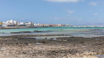 Un paisaje urbano costero con edificios, un puerto deportivo y un litoral rocoso.