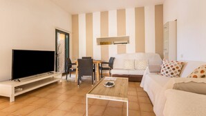 Una sala de estar con televisor, sofá, mesa de centro y paredes a rayas.