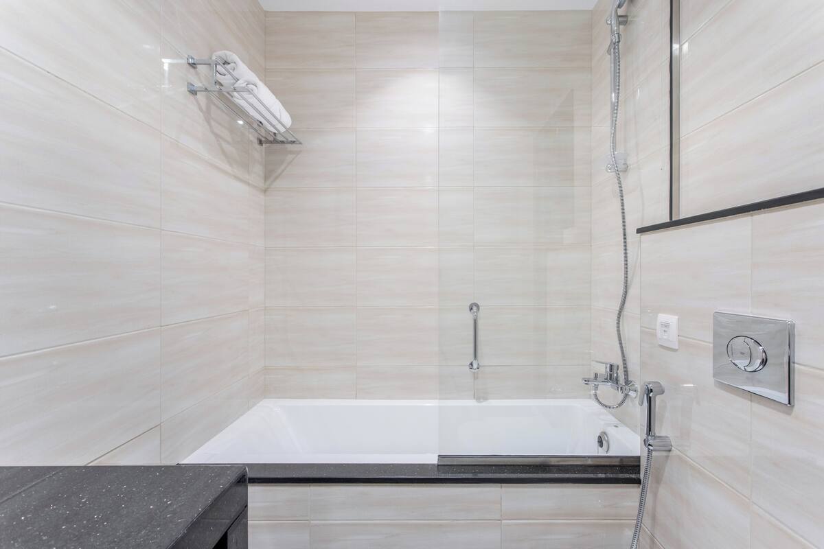 A modern bathroom with a bathtub, a shower, and a towel rack.
