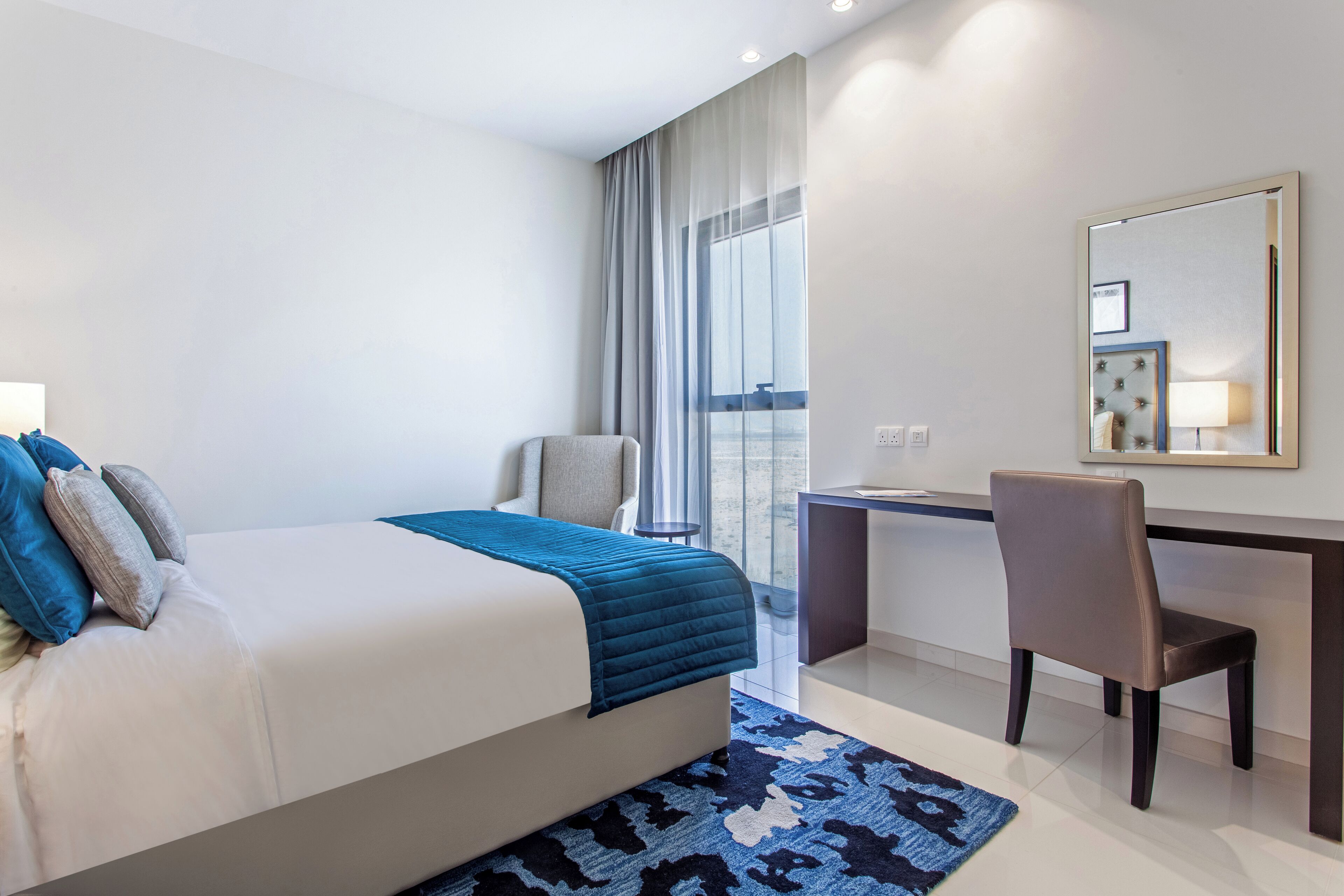 Quarto de hotel moderno com uma cama grande, uma escrivaninha e uma cadeira.