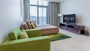 A modern living room with a green sofa, a brown sofa, a flat-screen TV, and a large window with curtains. - Staycae Celestia (Dubai)