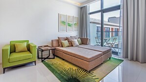 A modern hotel room with a large bed, a green armchair, and a view of the city through large windows. - Staycae Celestia (Dubai)