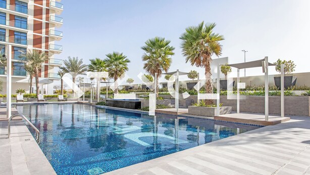 A swimming pool with a tiled deck, surrounded by palm trees and modern buildings. - Staycae Celestia (Dubai)