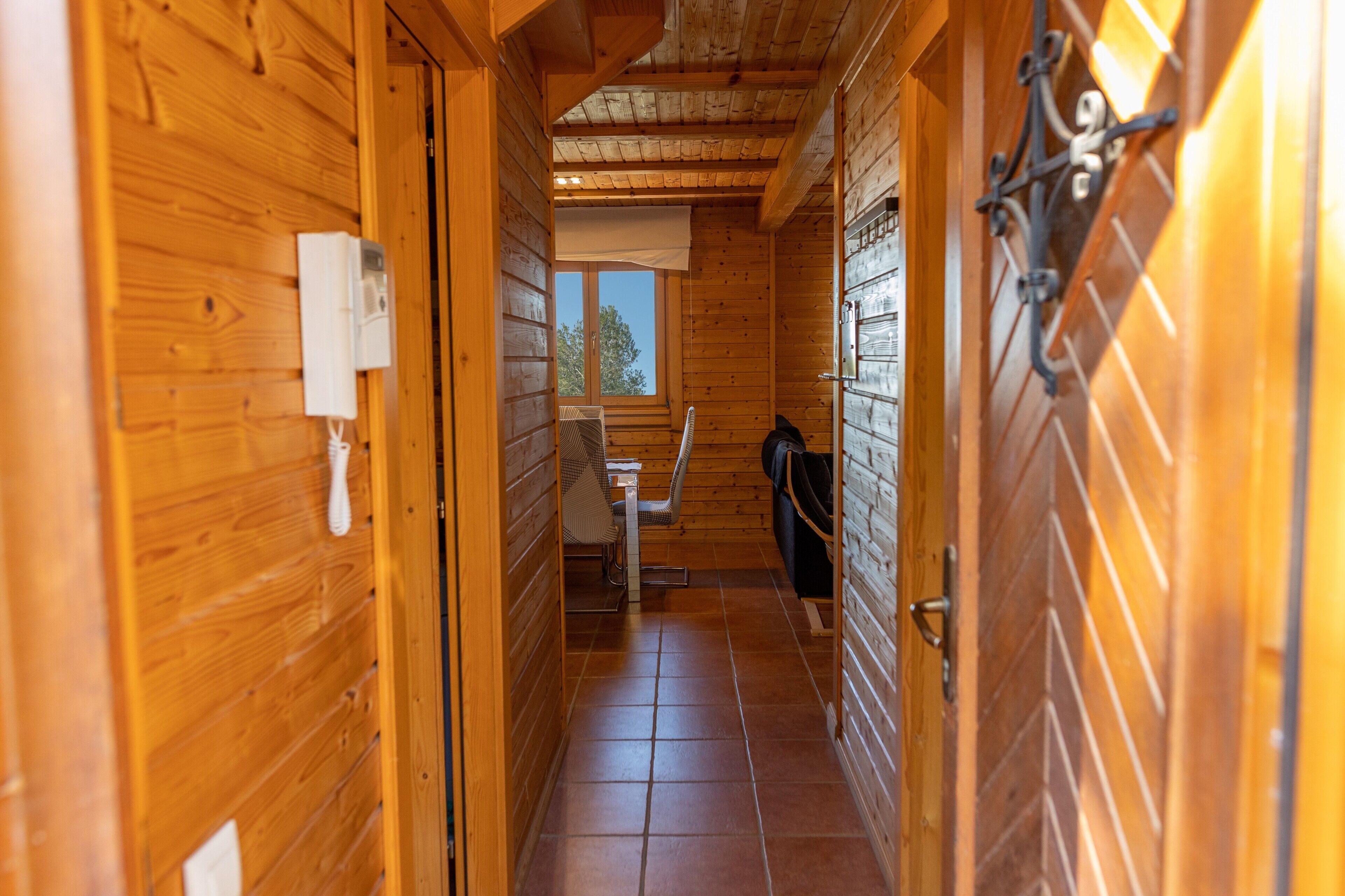 A narrow wooden hallway with a window, a chair, and a table.
