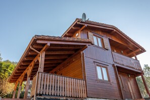 A wooden cabin with a balcony, a satellite dish, and a window. - Chalet 'Casa de Madera' with Mountain View, Garden, A/C, Pool & Wi-Fi (Calafell)