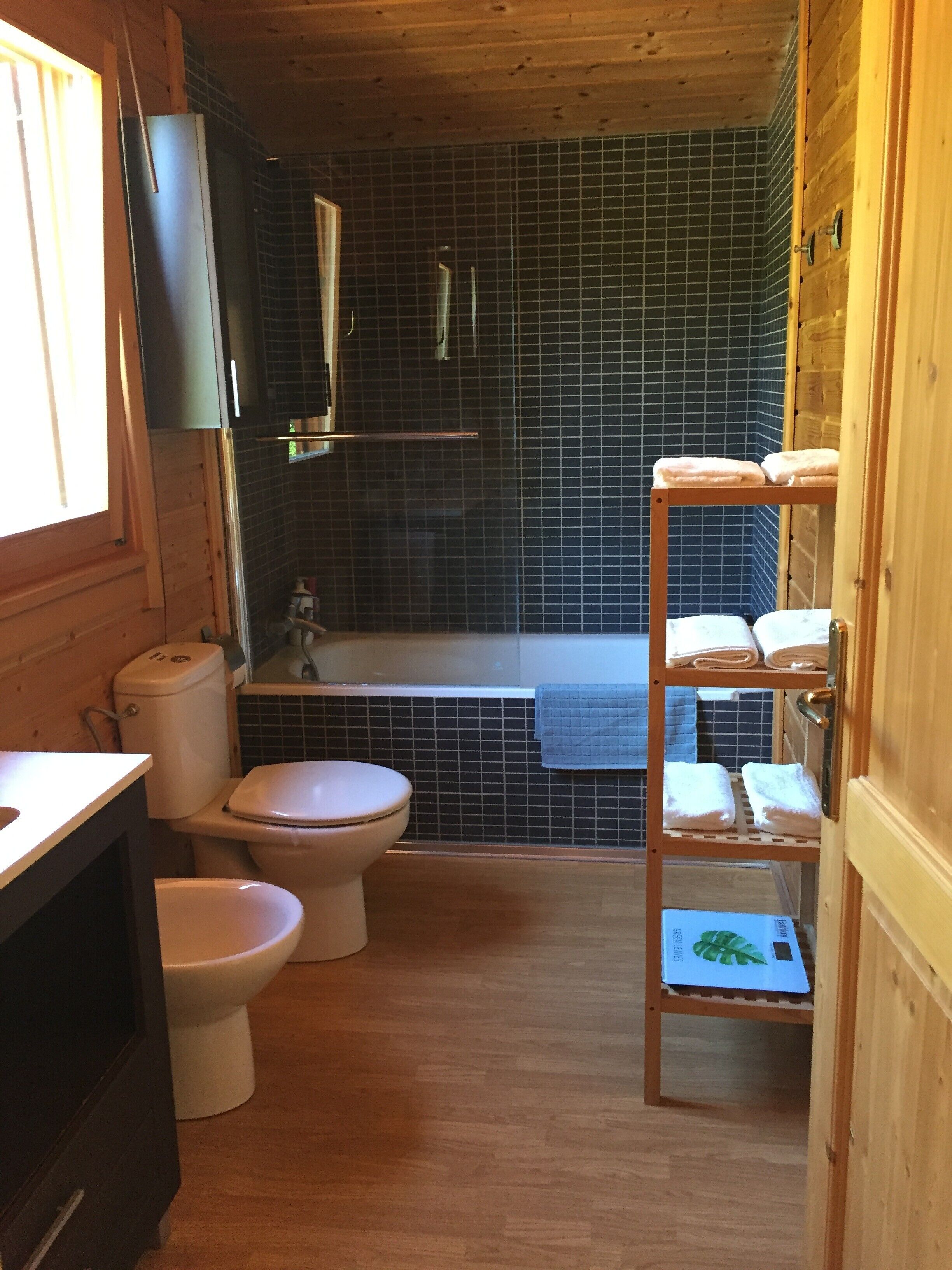 A compact bathroom with a toilet, bidet, and a small shelf with towels.