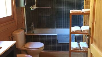 A compact bathroom with a toilet, bidet, and a small shelf with towels.
