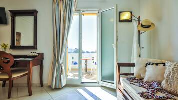 Ein Zimmer mit Schreibtisch, Stuhl, Bett und Blick durch eine offene Tür.