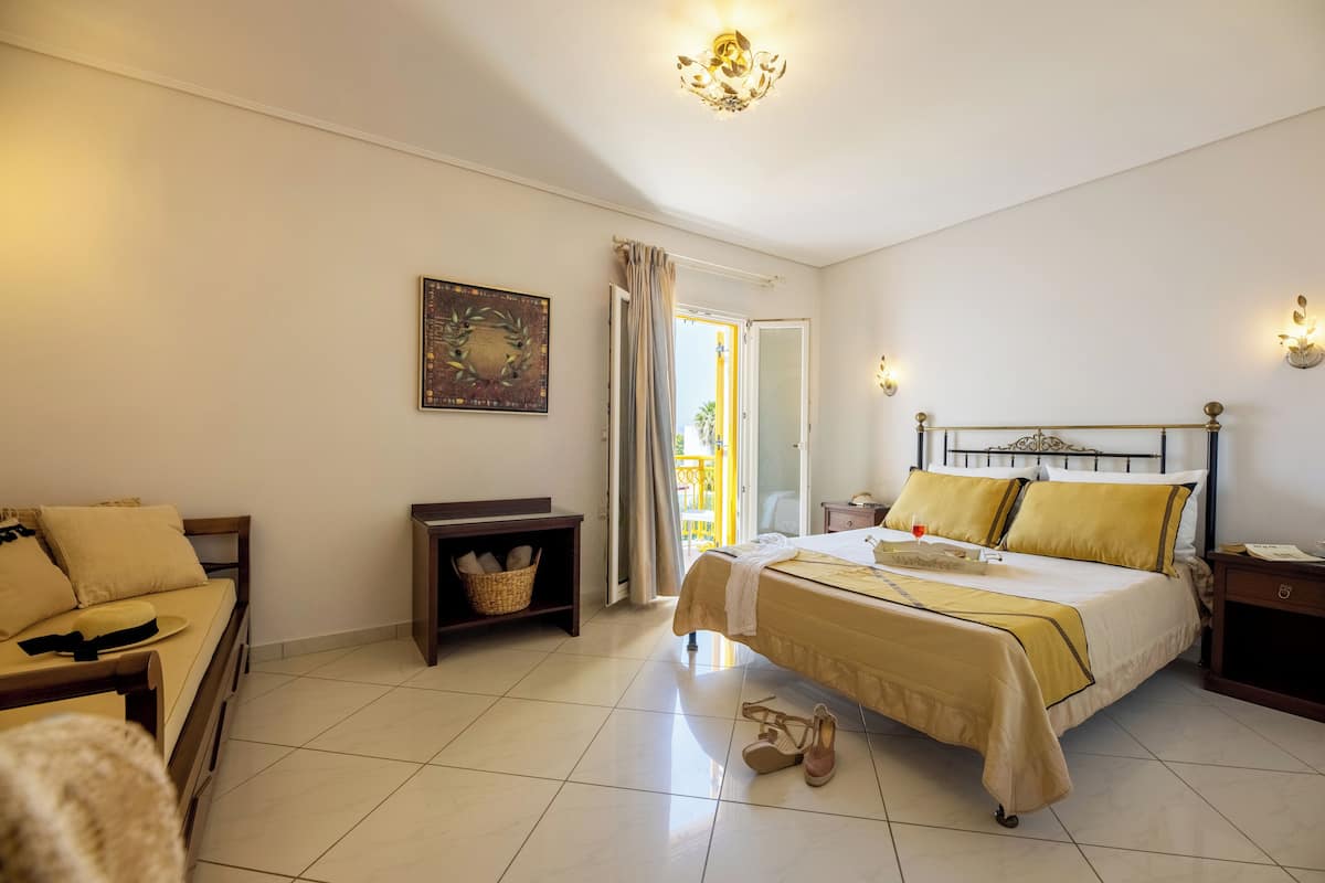 A hotel room with a bed, a sofa, a small table, a nightstand, and a window with curtains.