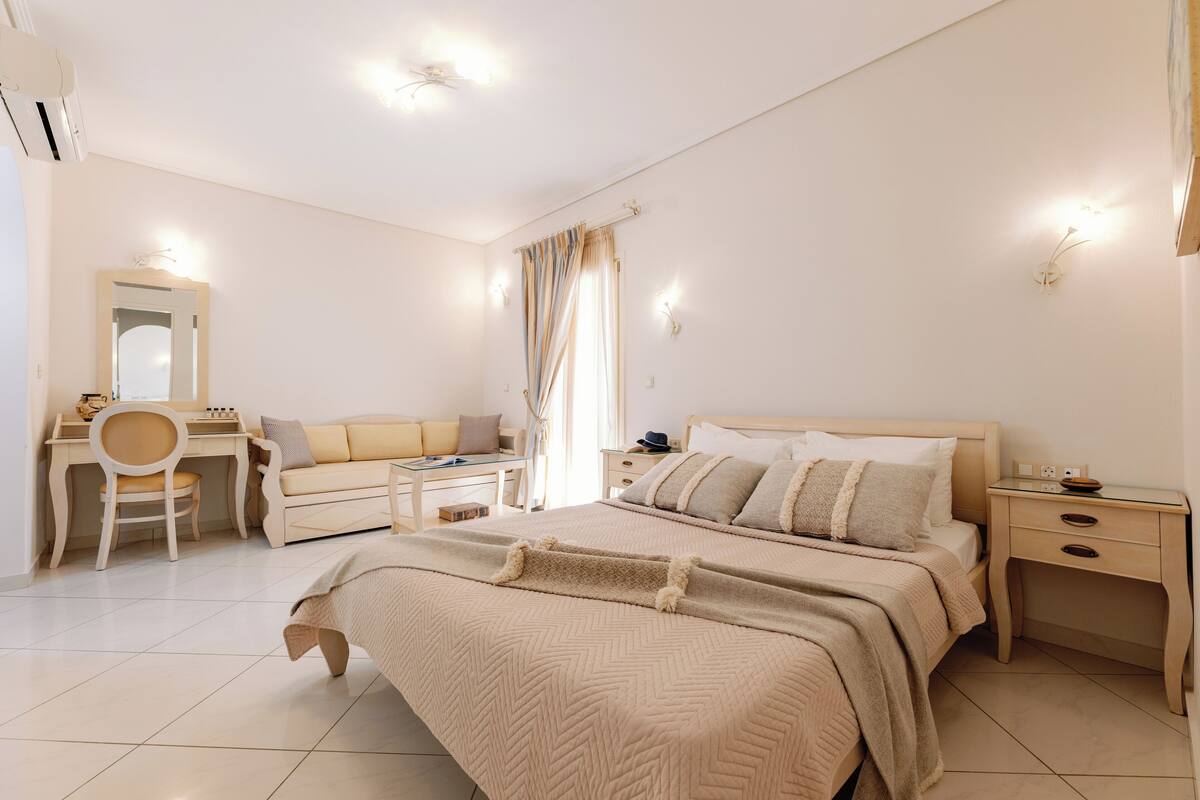 A bedroom with a bed, bedside tables, a desk, a chair, and a mirror.