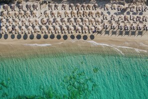 Vista aérea de una playa con hileras de sombrillas y sillas de playa.