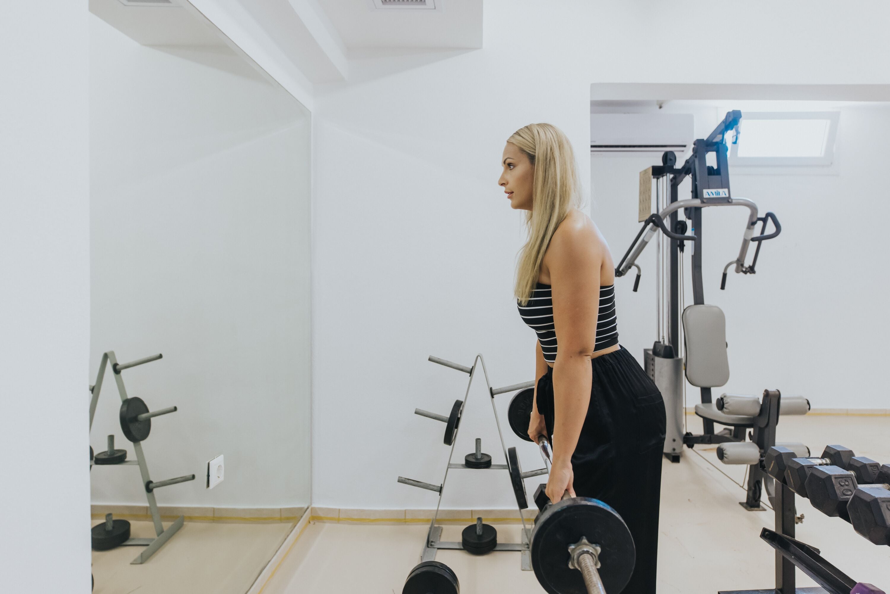 Un gimnasio con equipo de levantamiento de pesas, incluyendo mancuernas y una estructura para sentadillas.
