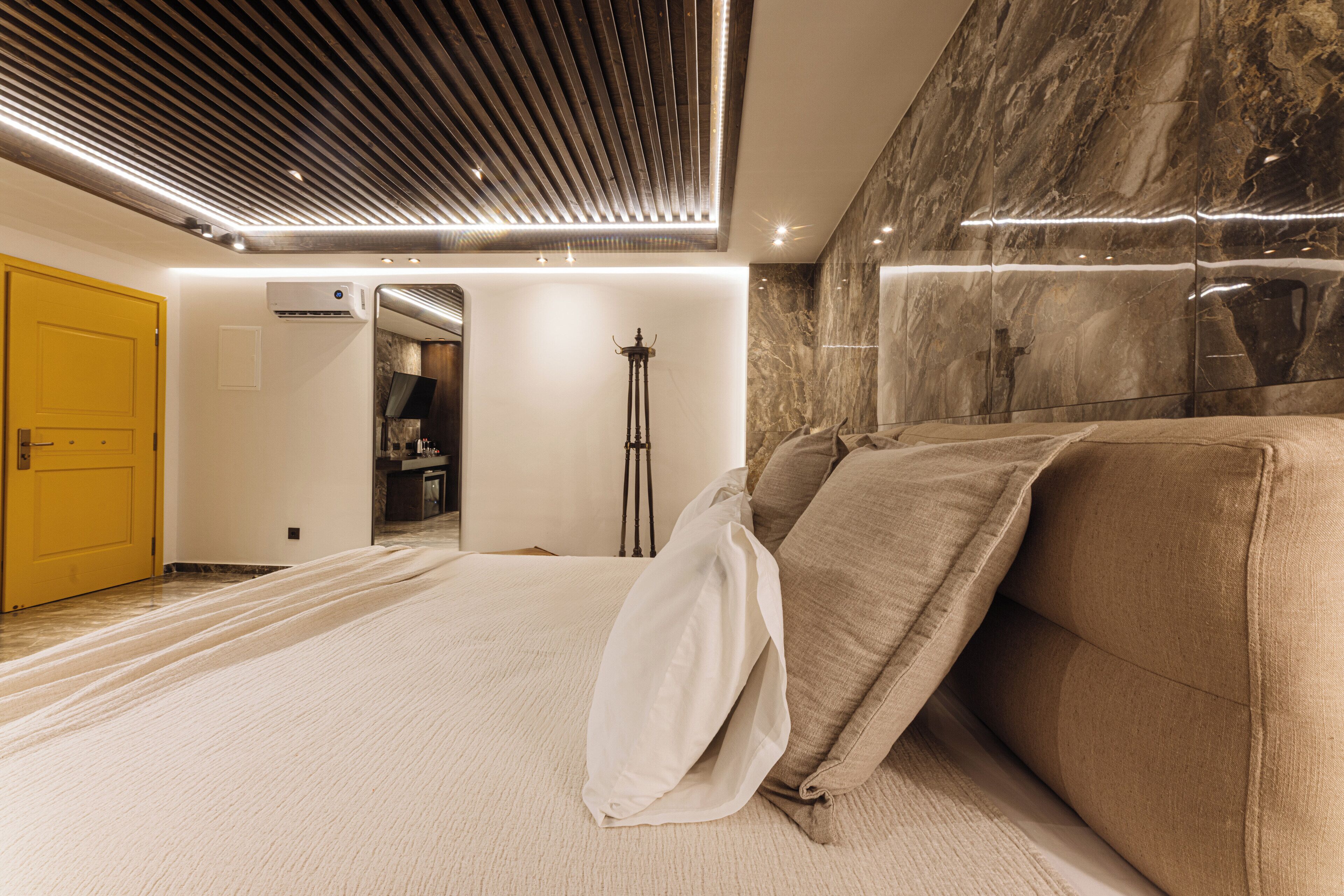 Une chambre moderne avec un grand lit, une lampe sur pied et un mur en marbre.