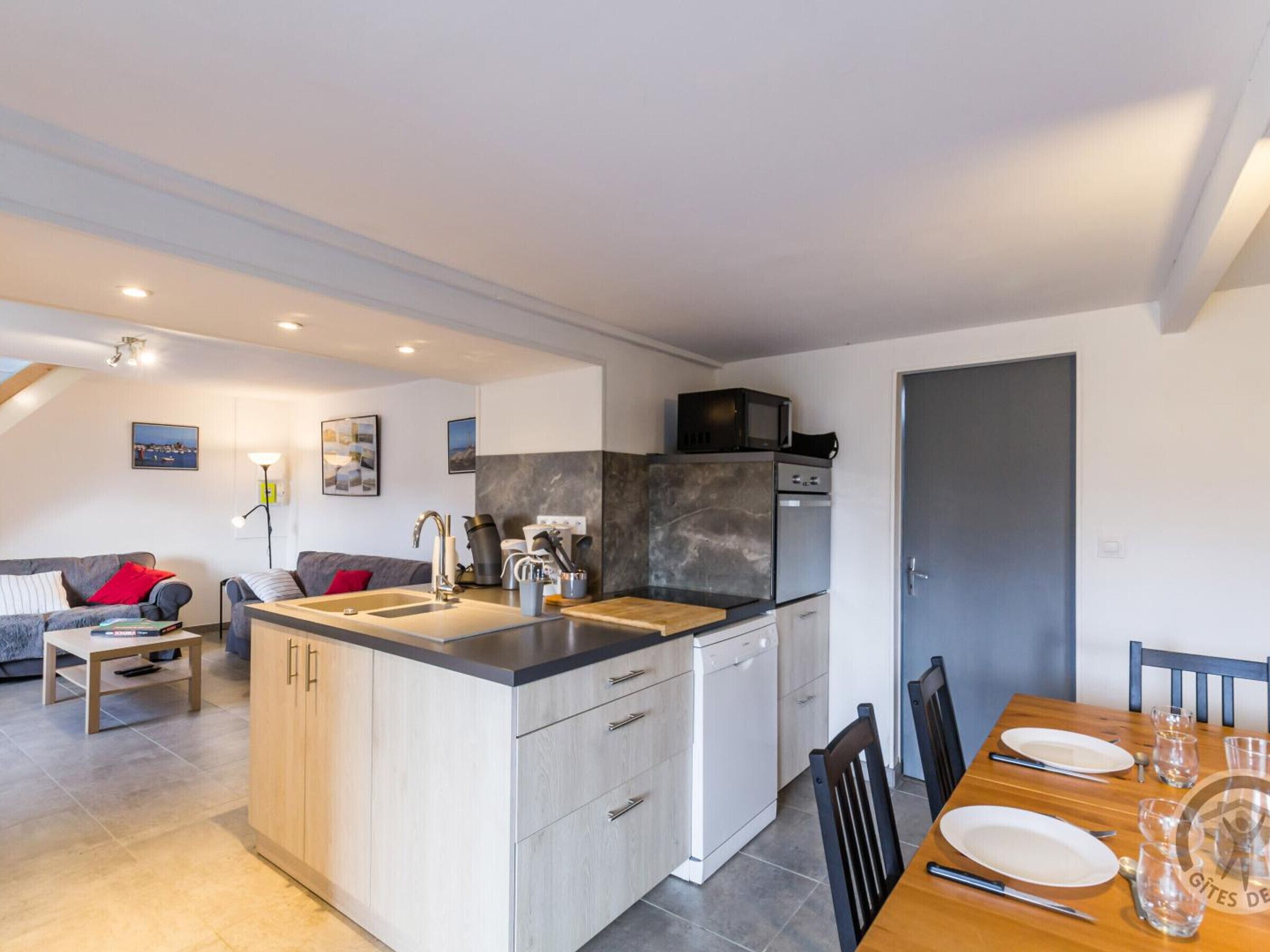 A modern kitchen with a central island, built-in appliances, and a dining area with a table set for two.
