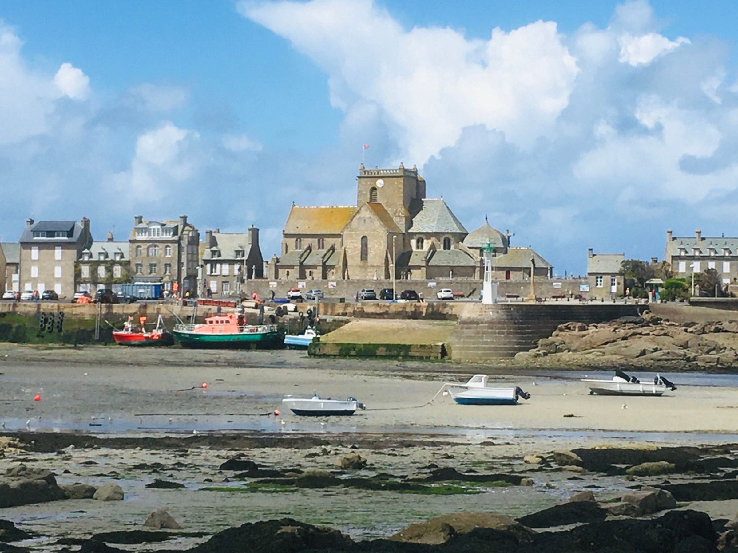 Une ville côtière qui se distingue par son église imposante, les bateaux amarrés sur la plage et son rivage rocheux.