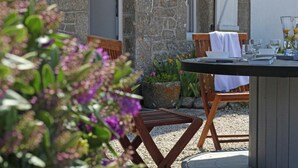 An outdoor dining area with a stone wall, wooden chairs, and a table set for two. - Seaside house with beach access, modern amenities and family space (Gatteville-le-Phare)