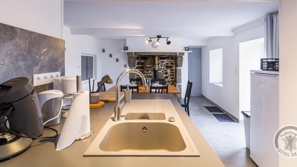 Una cocina moderna con una isla central, horno empotrado y pared de piedra.