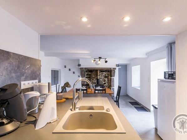Una cocina moderna con una isla central, horno empotrado y pared de piedra.