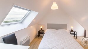 A bedroom with a skylight, a bed, two bedside tables with lamps, and a view of the outdoors. - Seaside house with beach access, modern amenities and family space (Gatteville-le-Phare)
