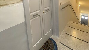 Eine Treppe mit Handlauf, eine weiße Tür und ein gemustertes Teppich am Fuß.