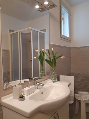 A modern bathroom with a large mirror, a sink, and a window. - Apartment in villa with private veranda and free private parking space (Olbia)