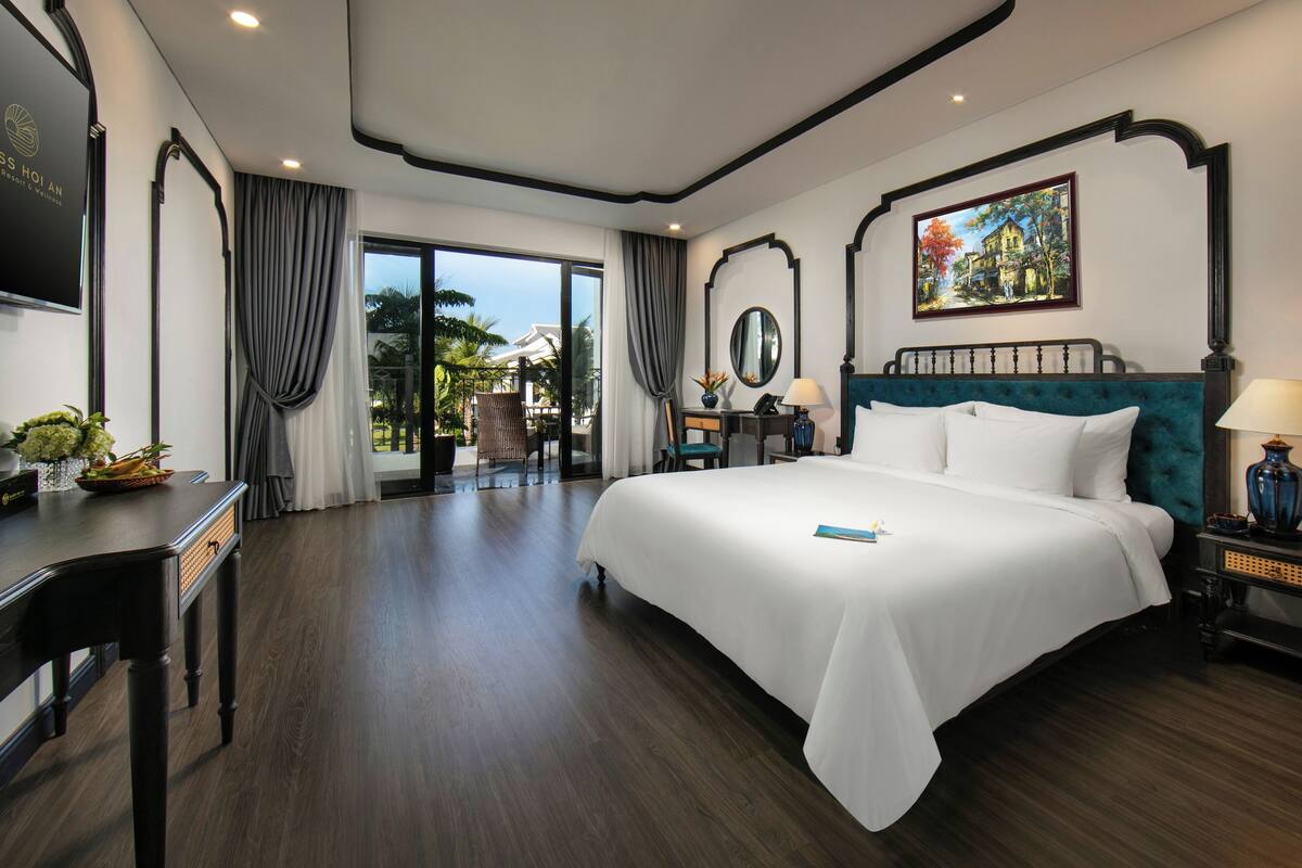 Une chambre d’hôtel avec un grand lit, un bureau, une chaise, une télévision et un tableau au mur.