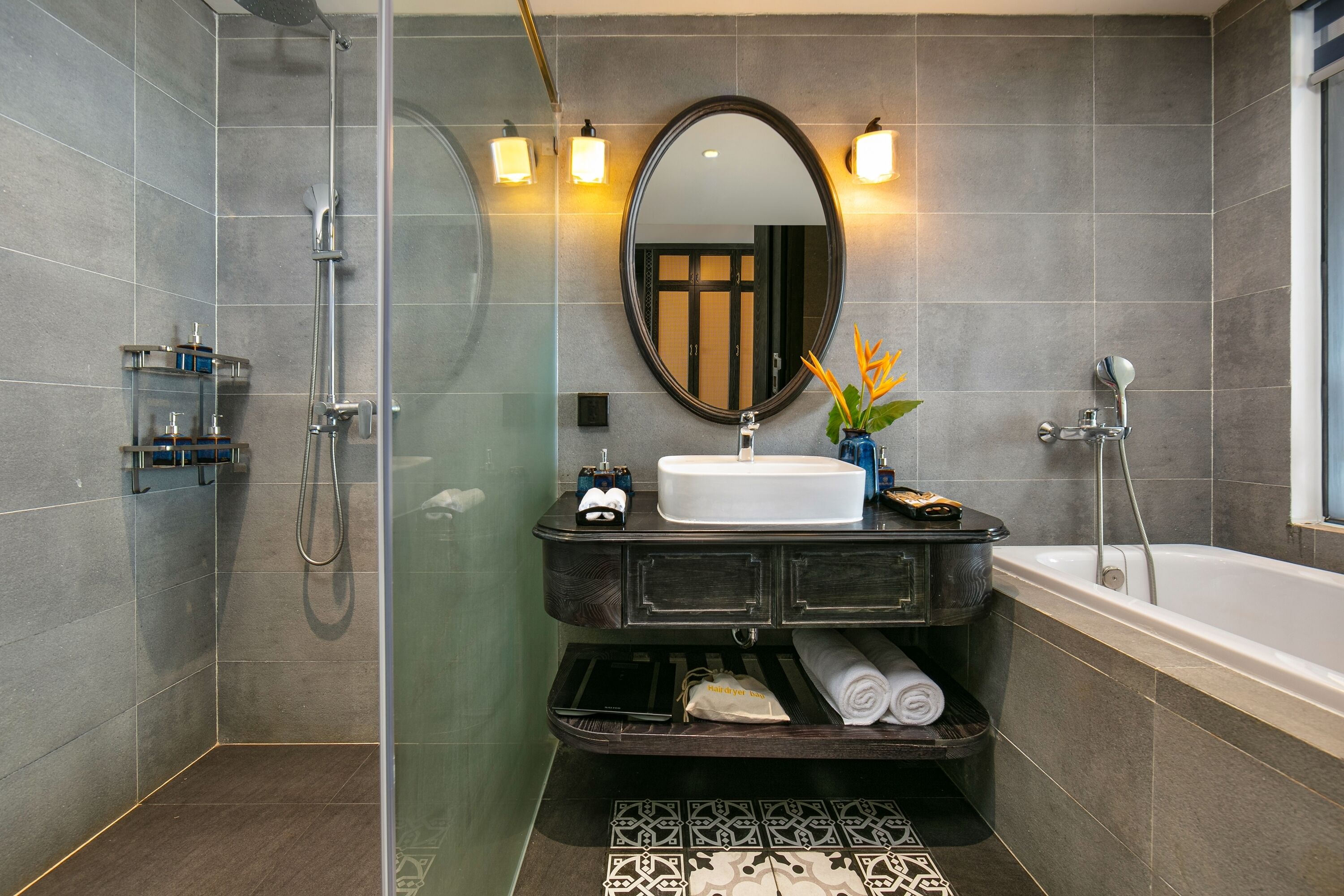 A modern bathroom with a glass-enclosed shower, a large mirror, and a bathtub.