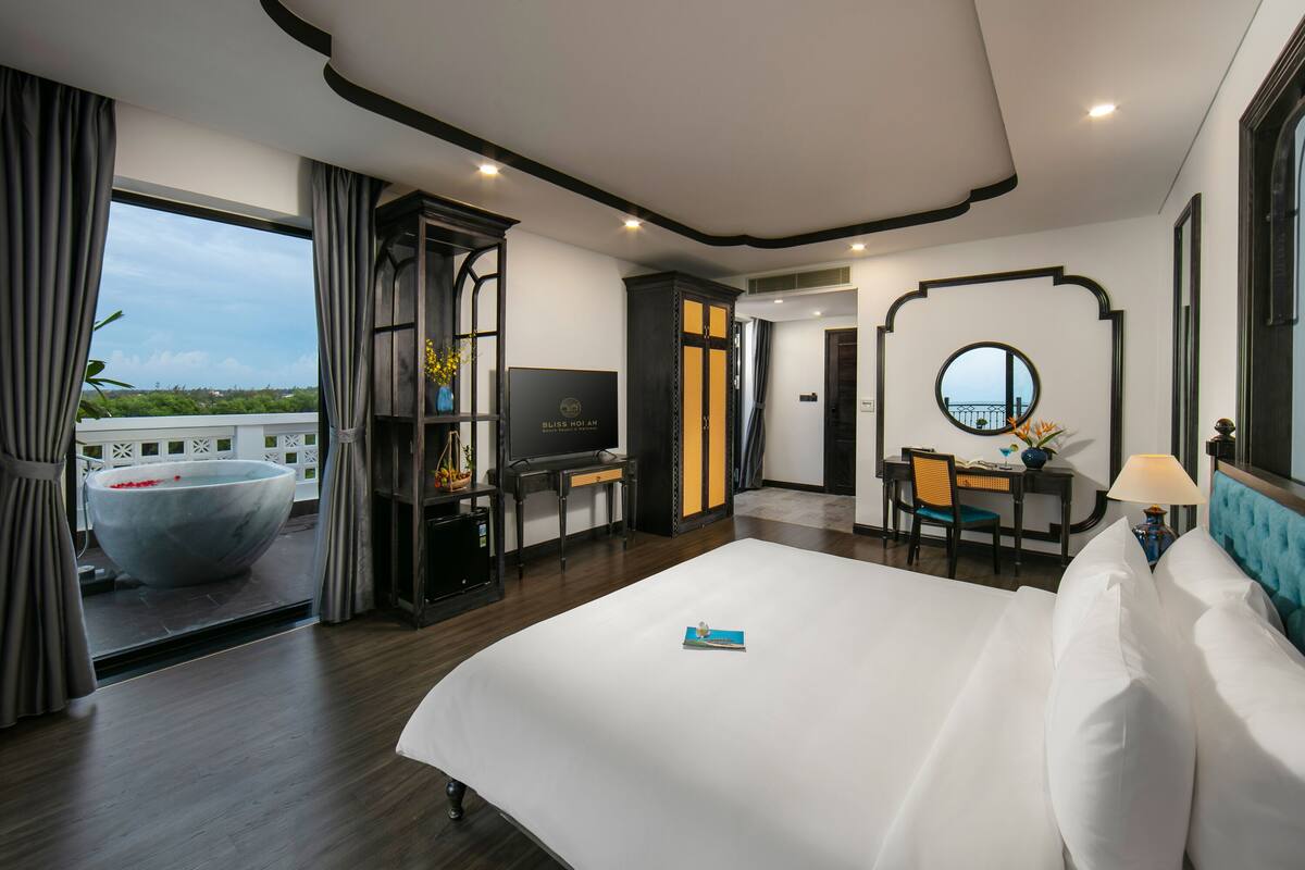 Une chambre d’hôtel avec un grand lit, un bureau avec une chaise, une télévision et une vue sur l’extérieur.