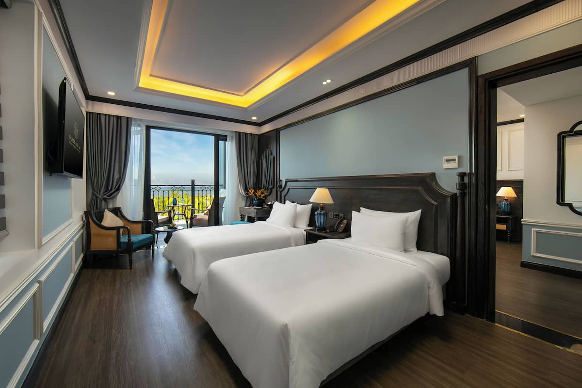 Une chambre d’hôtel avec deux lits, une télévision, un bureau et une vue sur la ville.