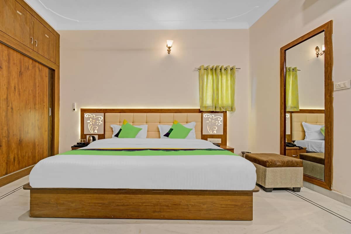 A bedroom with a large bed, wooden wardrobe, and a mirror.